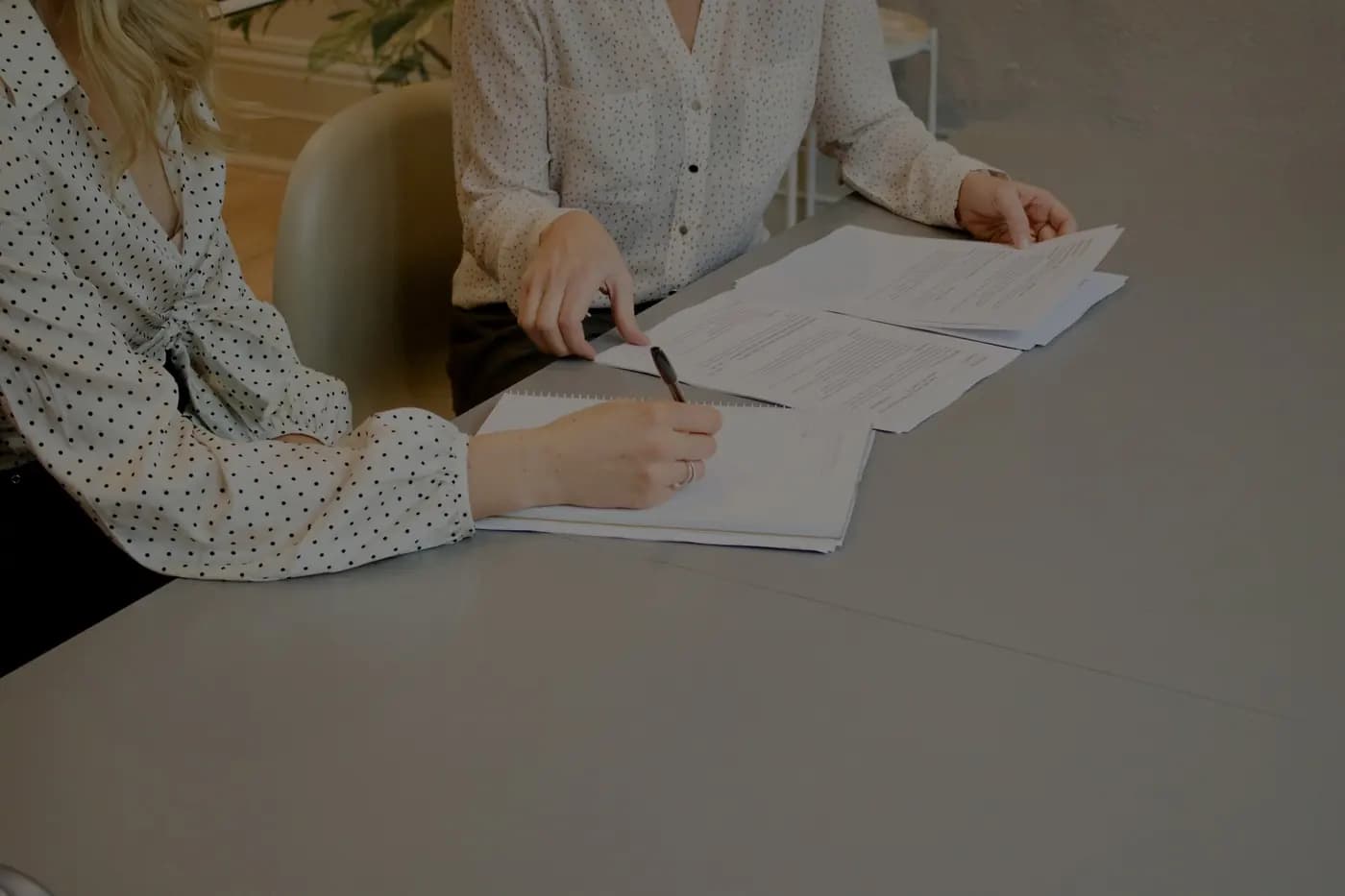 Two people going through a written schedule of works at a table